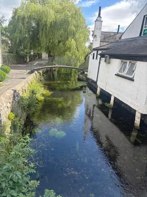 a river with a bridge next to a building at Grayrigge Croft Cottage in Grange Over Sands