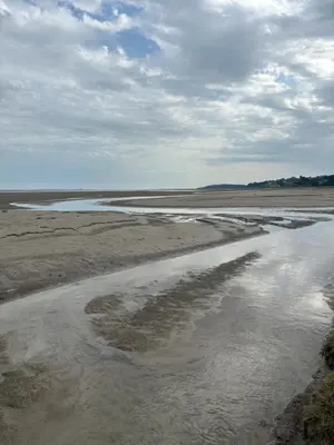 a body of water on a beach with a cloudy sky at Grayrigge Croft Cottage in Grange Over Sands