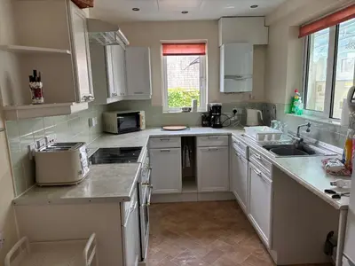 a kitchen with white cabinets and a sink at Grayrigge Croft Cottage in Grange Over Sands