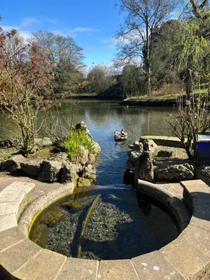 a pond in a garden next to a river at Grayrigge Croft Cottage in Grange Over Sands