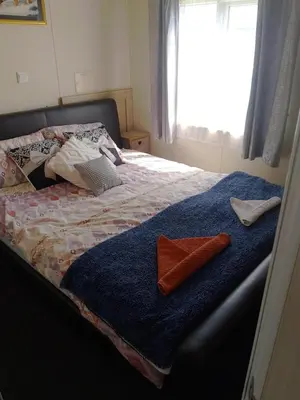 a bed with a blue comforter and two towels on it at Happy Go Lucky Lodge in Middleton