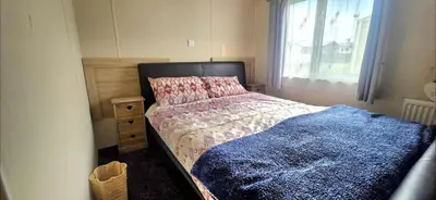 a bedroom with a bed with a blue blanket and a window at Happy Go Lucky Lodge in Middleton