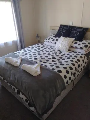 a large bed with black and white sheets and pillows at Happy Go Lucky Lodge in Middleton