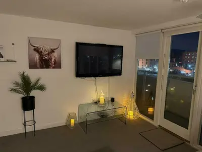 a living room with a glass table and a flat screen tv at 5 star Luxury Apartment in City Centre with views in Liverpool