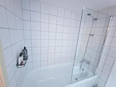 a white tiled bathroom with a shower and a tub at 5 star Luxury Apartment in City Centre with views in Liverpool
