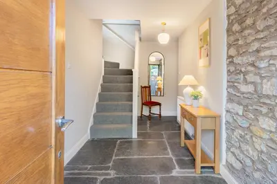 a hallway with a staircase and a stone wall at Royal Oak Barn - Cartmel, Sleeps 8 NEW in Cartmel