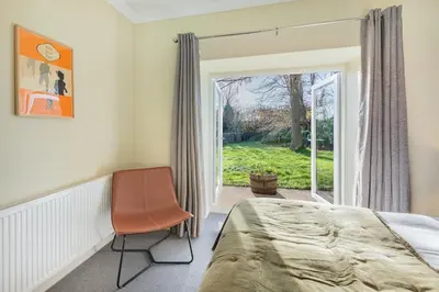 a bedroom with a bed and a chair and a window at Royal Oak Barn - Cartmel, Sleeps 8 NEW in Cartmel