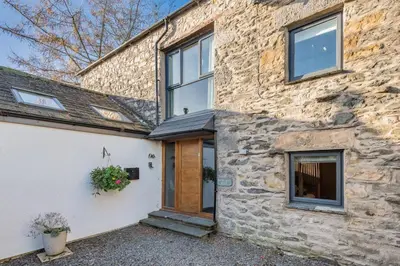 a stone house with a wooden door and windows at Royal Oak Barn - Cartmel, Sleeps 8 NEW in Cartmel
