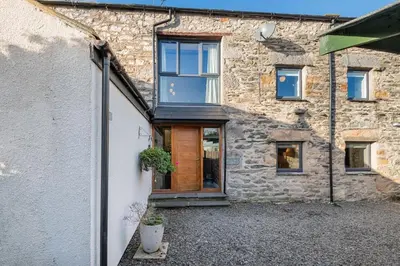 a stone house with a wooden door and windows at Royal Oak Barn - Cartmel, Sleeps 8 NEW in Cartmel