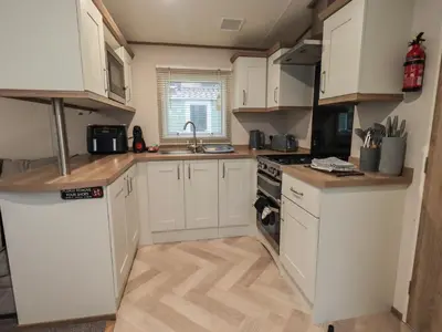 a small kitchen with white cabinets and a sink at Foxwood Hideaway in Carnforth