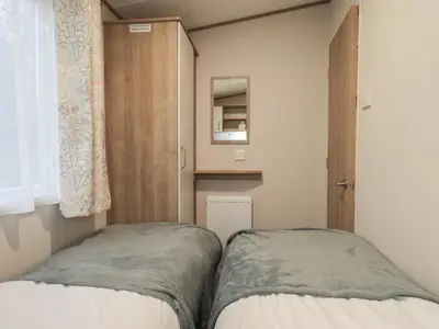 two beds in a small room with a mirror at Foxwood Hideaway in Carnforth