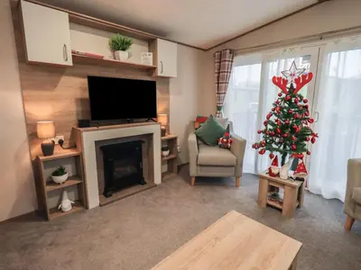 a living room with a christmas tree and a television at Foxwood Hideaway in Carnforth