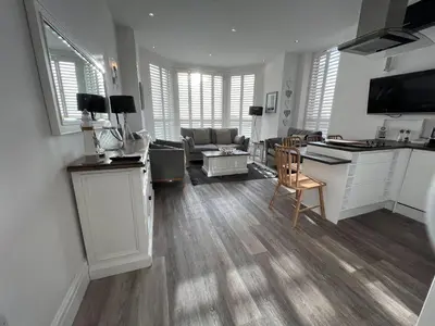 a kitchen and living room with white cabinets and a table at St Annes Beach Apartments in Lytham St Annes