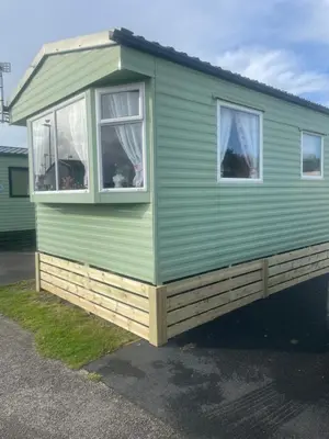 a green tiny house with two windows at Gemini in Heysham