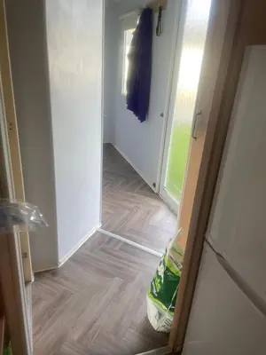 a hallway with a door open to a room with wood floors at Gemini in Heysham