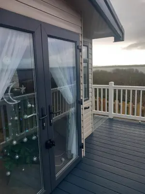 a glass door on a deck with a balcony at The Bluebell in Haverigg
