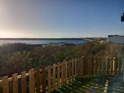 a wooden fence next to a body of water at The Bluebell in Haverigg