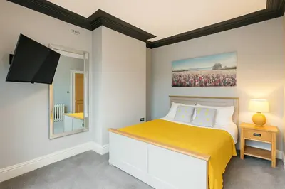 a bedroom with a bed with a yellow blanket at Large 6 Bed Southport Coastal Retreat with Sauna in Southport