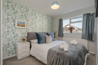 two beds in a bedroom with floral wallpaper at Moorland Bungalow Central Clitheroe in Clitheroe