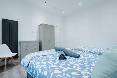 a bedroom with two beds and a dresser at Spacious 4 Bedroom House - Sleeps 10 Guests, Contractors, Groups, Families, Business, Travel, Leisure And Relocation Stays Welcome, 13 Mins From Liverpool City Centre, Fast Wi-Fi, Smart TV In Front Room & FREE Parking, Long Stays And Short Stays Welcome in Liverpool