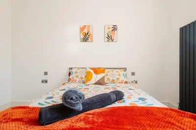 a bed with a towel laying on top of it at Spacious 4 Bedroom House - Sleeps 10 Guests, Contractors, Groups, Families, Business, Travel, Leisure And Relocation Stays Welcome, 13 Mins From Liverpool City Centre, Fast Wi-Fi, Smart TV In Front Room & FREE Parking, Long Stays And Short Stays Welcome in Liverpool