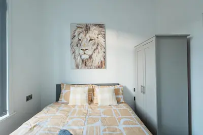 a bedroom with a bed with a lion picture on the wall at Spacious 4 Bedroom House - Sleeps 10 Guests, Contractors, Groups, Families, Business, Travel, Leisure And Relocation Stays Welcome, 13 Mins From Liverpool City Centre, Fast Wi-Fi, Smart TV In Front Room & FREE Parking, Long Stays And Short Stays Welcome in Liverpool