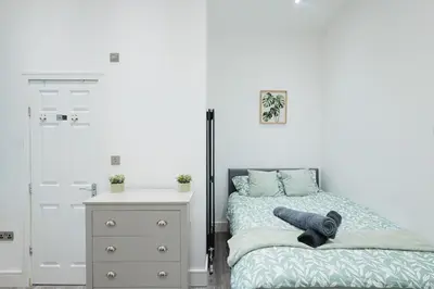 a bedroom with a bed with a teddy bear on it at Spacious 4 Bedroom House - Sleeps 10 Guests, Contractors, Groups, Families, Business, Travel, Leisure And Relocation Stays Welcome, 13 Mins From Liverpool City Centre, Fast Wi-Fi, Smart TV In Front Room & FREE Parking, Long Stays And Short Stays Welcome in Liverpool