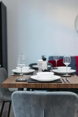 a table with plates and wine glasses on it at Spacious 4 Bedroom House - Sleeps 10 Guests, Contractors, Groups, Families, Business, Travel, Leisure And Relocation Stays Welcome, 13 Mins From Liverpool City Centre, Fast Wi-Fi, Smart TV In Front Room & FREE Parking, Long Stays And Short Stays Welcome in Liverpool