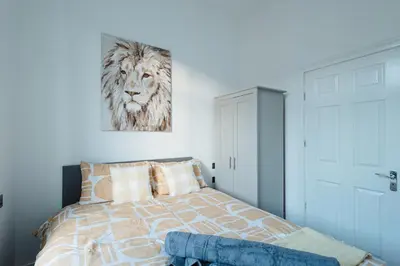 a bedroom with a bed with a painting of a lion at Spacious 4 Bedroom House - Sleeps 10 Guests, Contractors, Groups, Families, Business, Travel, Leisure And Relocation Stays Welcome, 13 Mins From Liverpool City Centre, Fast Wi-Fi, Smart TV In Front Room & FREE Parking, Long Stays And Short Stays Welcome in Liverpool