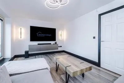 a living room with a table and a tv at Driveway Stunning 3Bedroom Home in Preston in Broughton