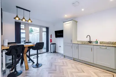 a kitchen with a wooden table and two black chairs at Driveway Stunning 3Bedroom Home in Preston in Broughton
