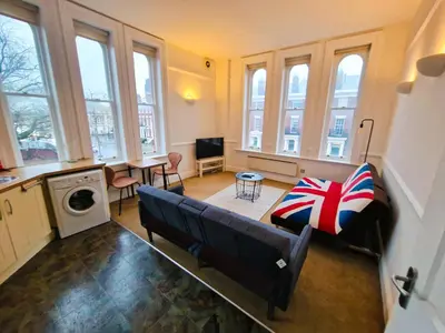 a living room with a couch and a table and windows at Modern Victorian Charm in a Great Location in Liverpool