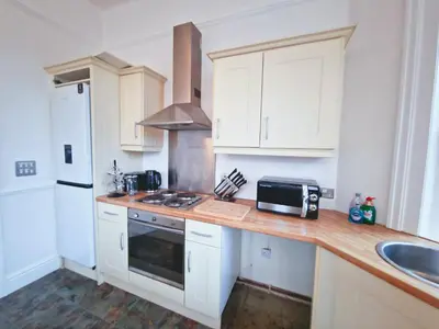 a kitchen with white cabinets and a counter top with a microwave at Modern Victorian Charm in a Great Location in Liverpool