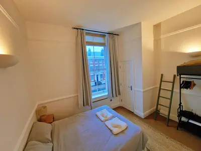 a small bedroom with a bed and a window at Modern Victorian Charm in a Great Location in Liverpool
