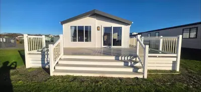 a small white house with a porch and stairs at Bay View Lodge in Heysham