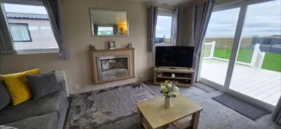 a living room with a television and a fireplace at Bay View Lodge in Heysham