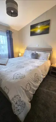 a bedroom with a large white bed with two teddy bears on it at Bay View Lodge in Heysham