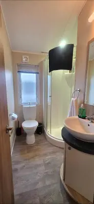 a bathroom with a toilet and a shower and a sink at Bay View Lodge in Heysham