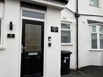 a black door on a white house with a trash can at Cleveleys Town Centre in Blackpool