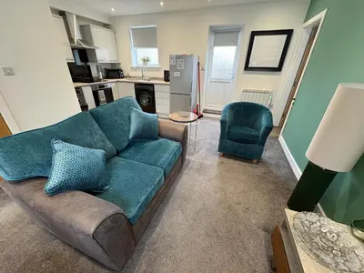 a living room with a blue couch and a kitchen at Cleveleys Town Centre in Blackpool