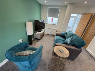 a living room with two blue chairs and a table at Cleveleys Town Centre in Blackpool