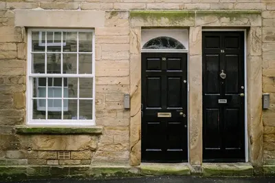 two black doors on a stone building with windows at Sun Street Retreats in Lancaster