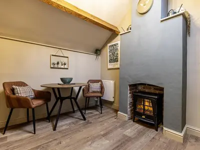 a living room with a table and a fireplace at The Gardeners Cottage at Lytham Hall in Lytham St Annes