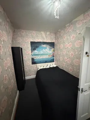 a small bedroom with pink flowers on the walls at Homey room in Liverpool