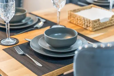 a wooden table with black plates and a bowl on it at Business Stays, Modern Liverpool Flat, sleeps 4 in Liverpool