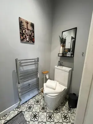 a bathroom with a white toilet and a mirror at Victoria suites in Southport