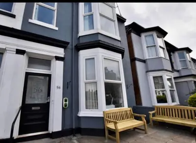 a blue house with two benches in front of it at Victoria suites in Southport