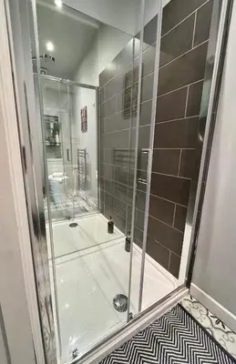 a shower with a glass door in a bathroom at Victoria suites in Southport