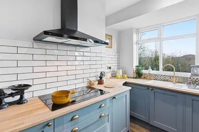 a kitchen with blue cabinets and a stove top oven at Spacious 4B home, great for contractors and families in Wigan