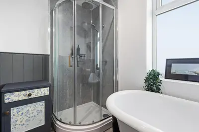 a bathroom with a shower and a tub and a sink at Spacious 4B home, great for contractors and families in Wigan